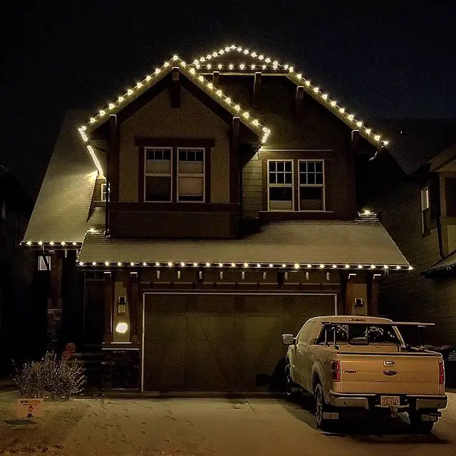 Warm white Christmas lights along the peaks and eaves of a two-storey home