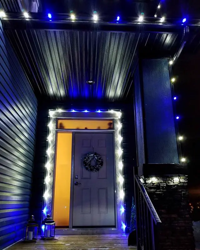 Blue and white Christmas lights framing a front door and porch